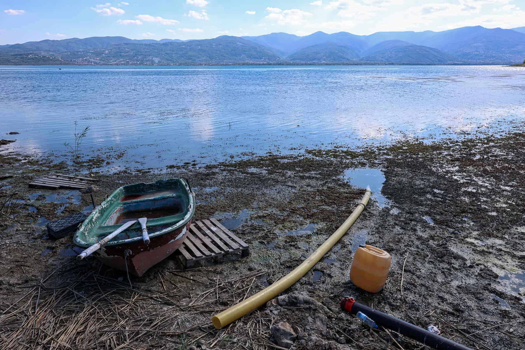 Göl kenarında eski tekne, su pompası ve doğa manzarası, doğal güzellikler ve su aktiviteleri ile ilgili rekabetçi SEO içerik.
