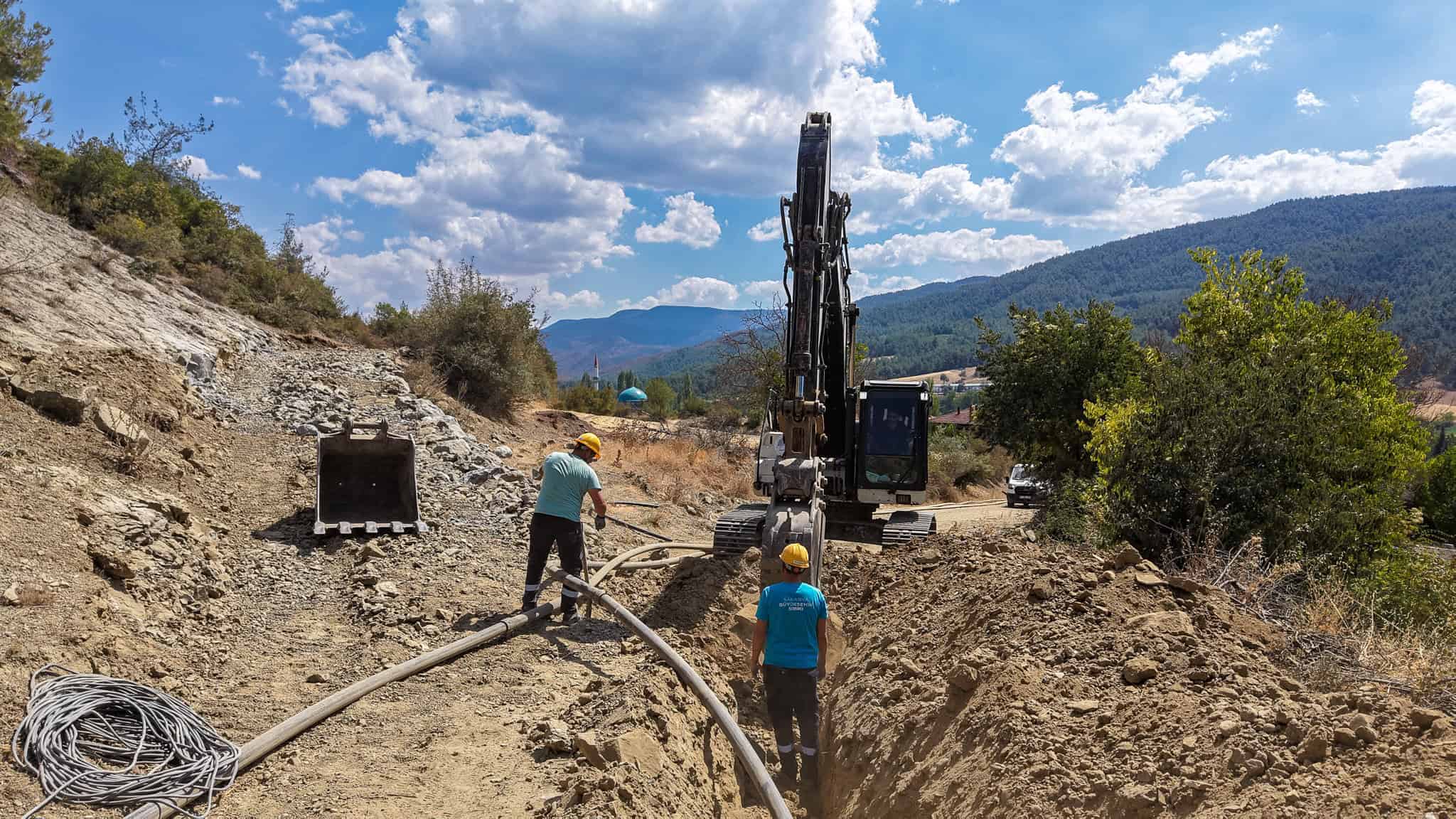 Çalışanlar ve iş makineleriyle altyapı çalışması, doğal ortamda inşaat faaliyetleri.