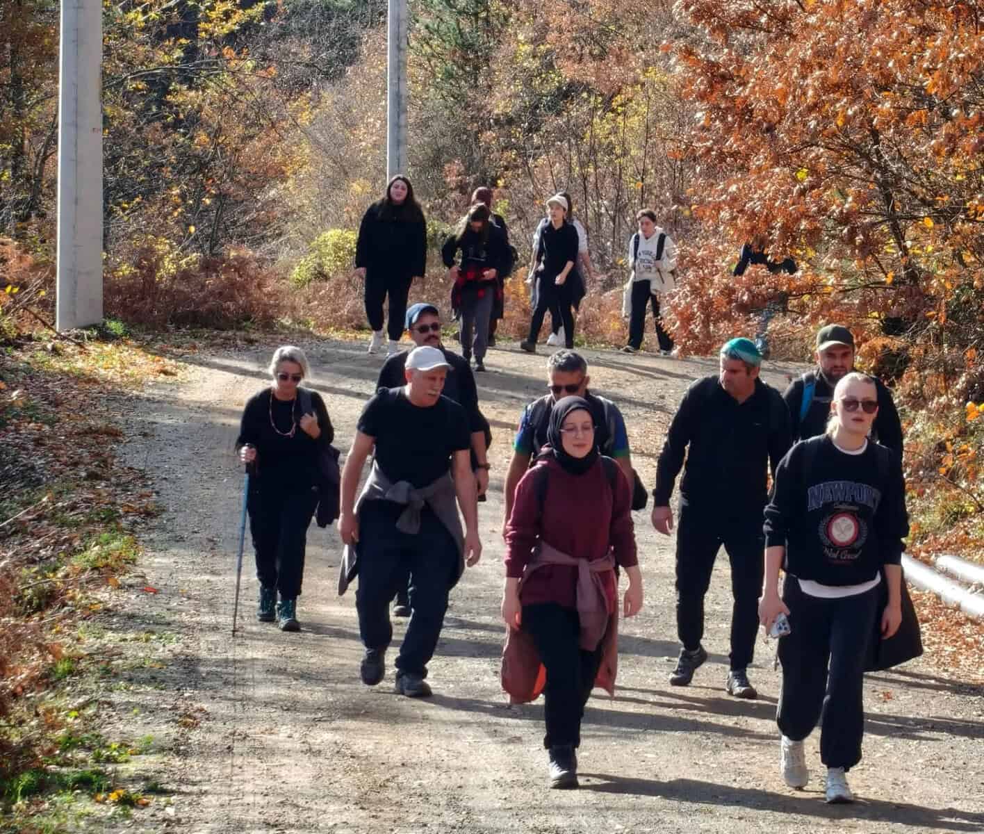 Ormanlıkta yürüyüş yapan kalabalık grup, sonbahar renkleri ve doğa manzarası.