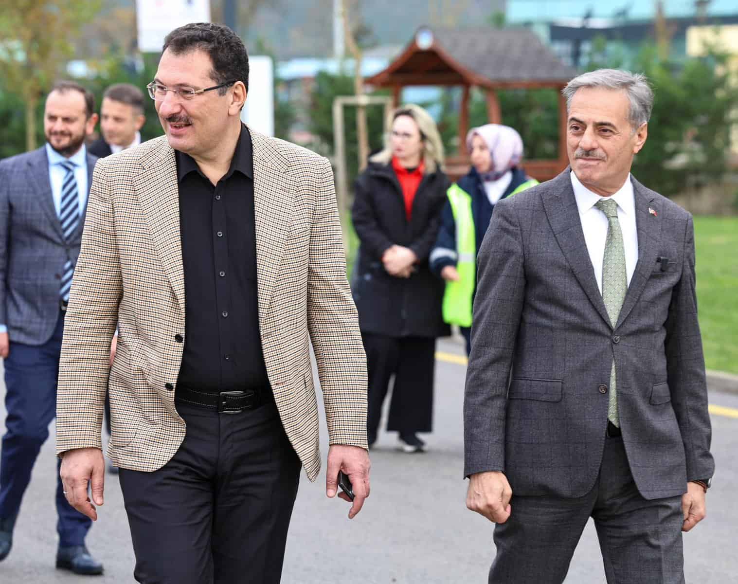 Başın Merkezi etkinliğine katılan resmi kişiler ve kalabalık grup dış mekanda samimi ortamda yürüyüş yaparken.