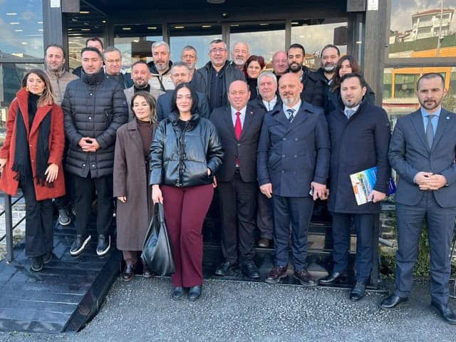 Bakımlı ve profesyonel kişilerden oluşan grup, Basın Merkezi önünde fotoğraf çekimi yapıyor.